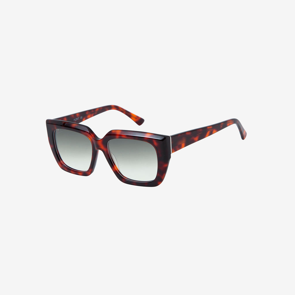 Tortoiseshell sunglasses with a thick frame and grey lenses rest against a white background.
